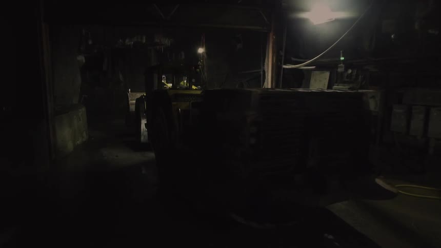 A bulldozer drives through a dark area at night