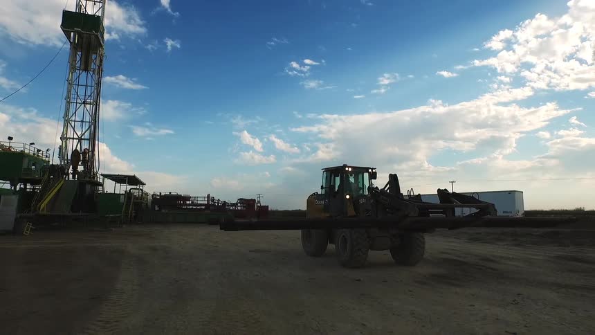 A forklift carries a large metal pole