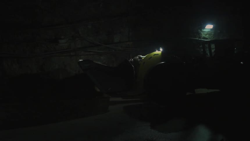 An underground front loader drives through a tunnel
