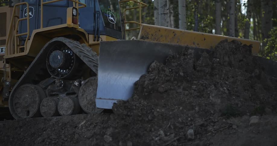 A bulldozer pushes a huge stack of rocks