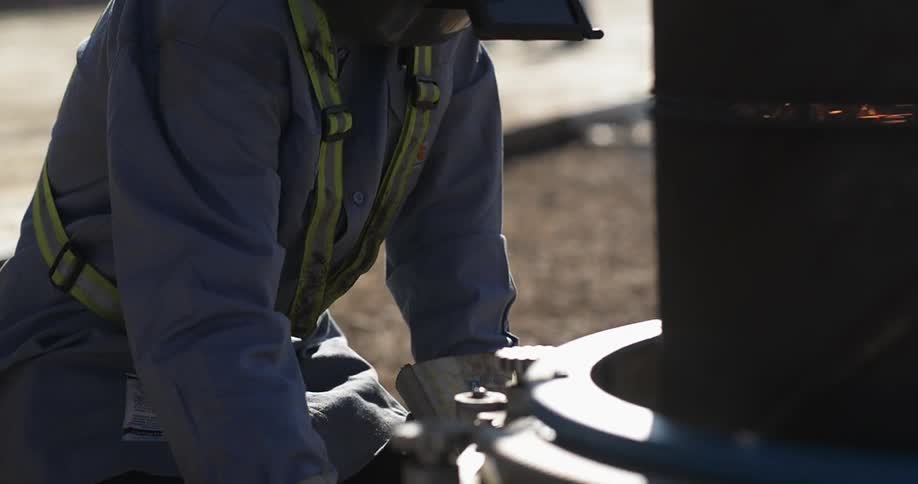 A man is cutting a metal tube with a torch