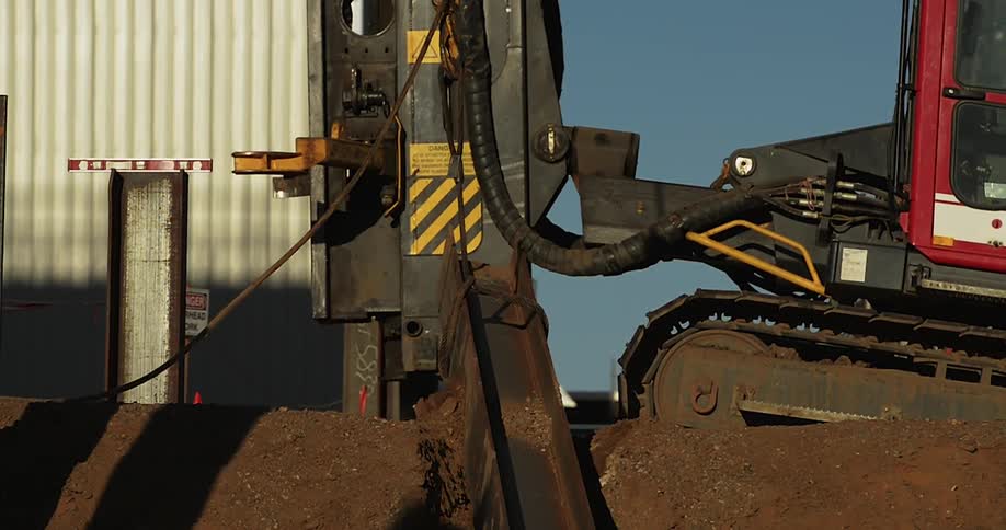 A construction machine is lifting a large beam