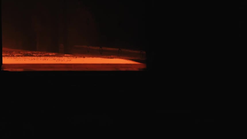 Red molten sheet runs down a conveyor belt