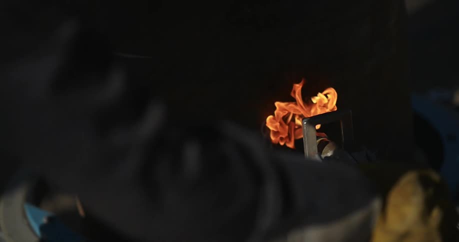 A worker uses a flaming torch in a factory