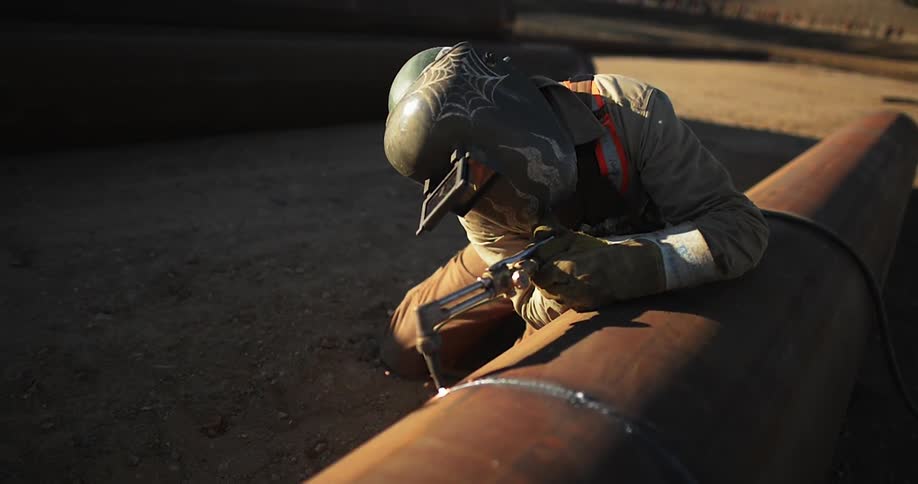 A man is working outside welding a pipe