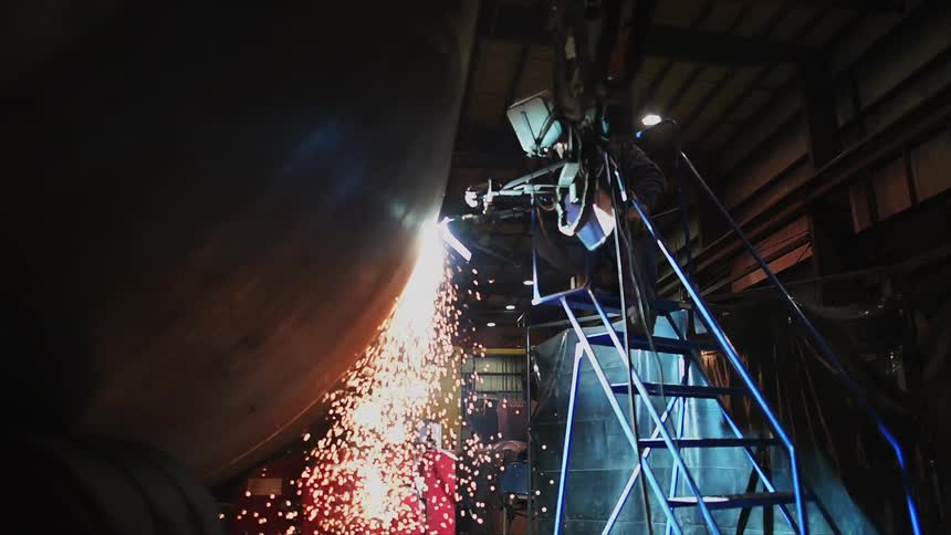 A welder is using a tool and creating sparks