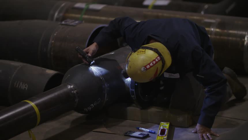 Person checks a large piece of metal with a flashlight