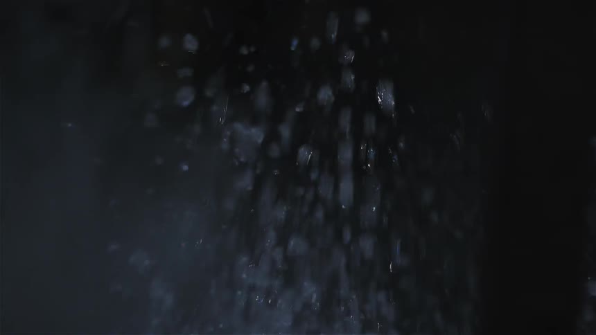 Water sprays around in a dark area