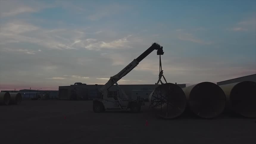 A crane is beginning to lift a large tube