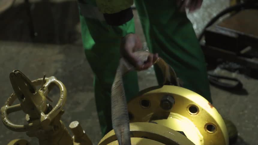 A worker ties a belt around a pipe