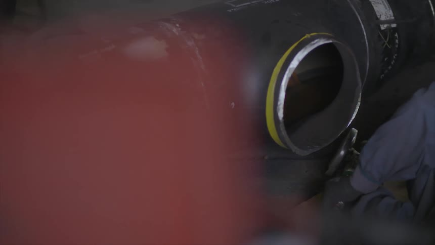 A worker grinds a piece of metal as sparks fly