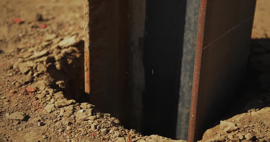 A metal beam pushes into the dirt