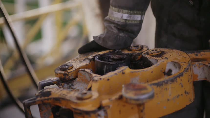 A worker puts a machine on a pipe