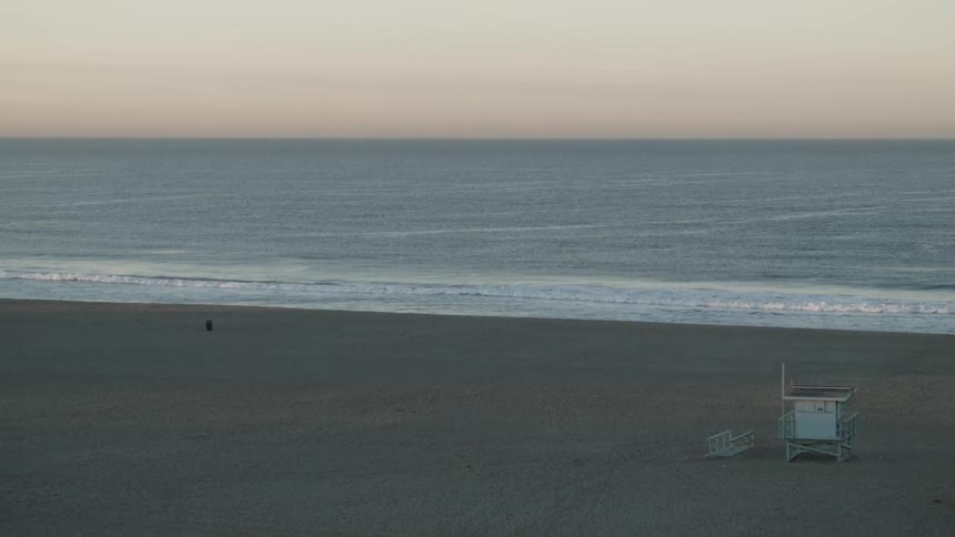 Ocean waves crash into a sandy beach at sunset