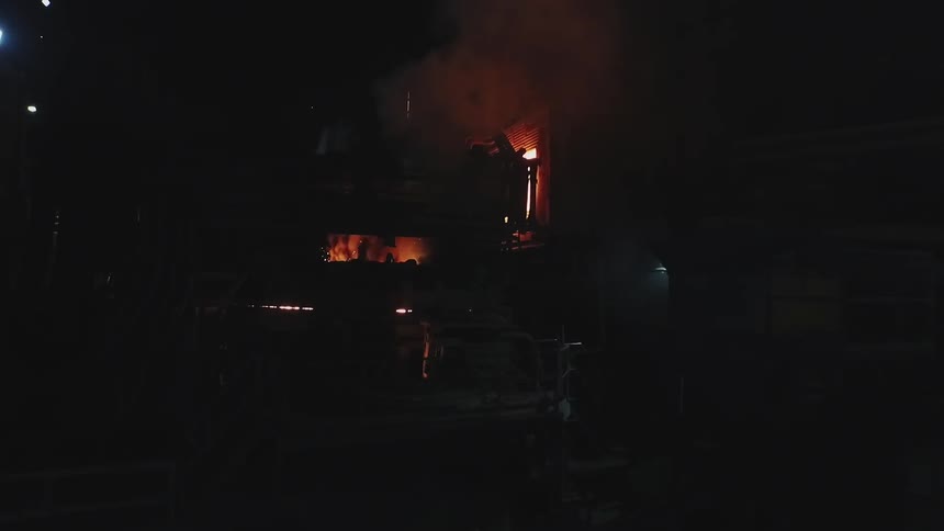 A fire burns inside a structure at night