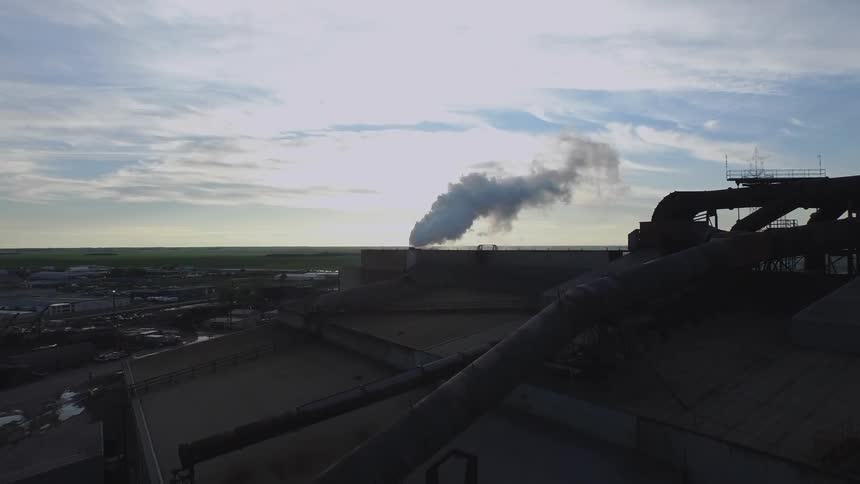 The warehouse is giving smoke into the cloudy sky from the chimney