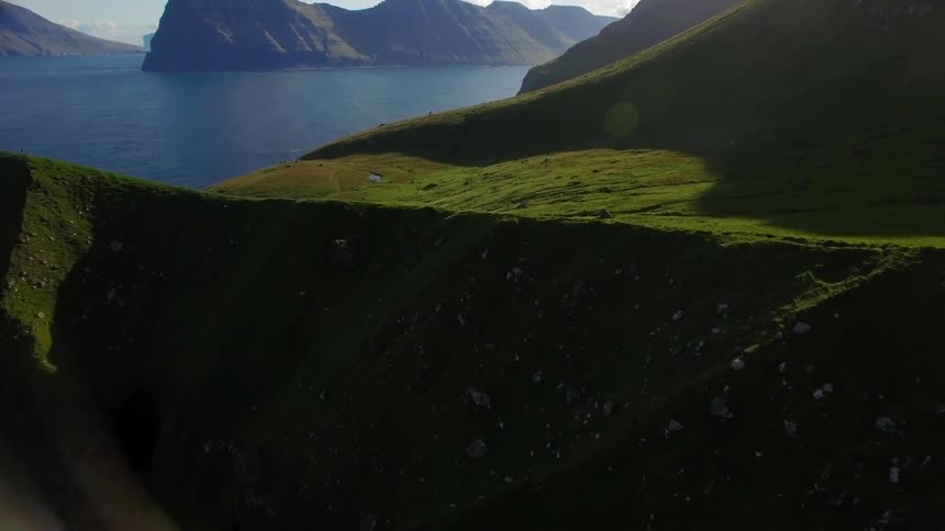 The mountains are covered with green with a small white tower at the top