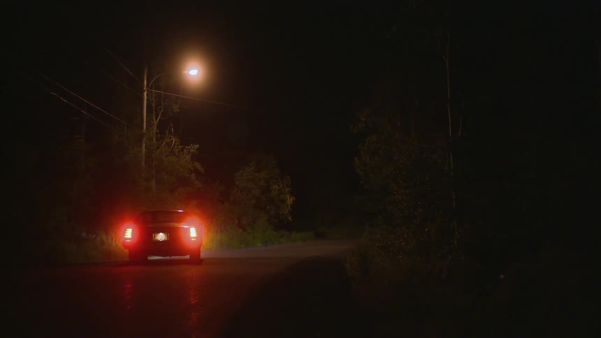 A car drives down the dark road