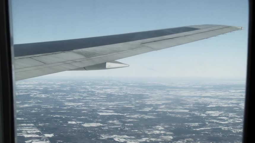 View of an airplane wing and the ground below