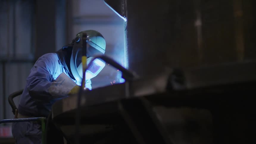 A worker is welding in a dark warehouse