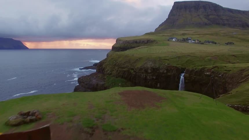 Person sits on a bench at the edge of a cliff overlooking a body of water