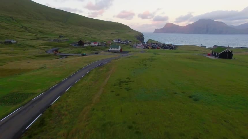 Person walks down small road to settlement of houses next to water