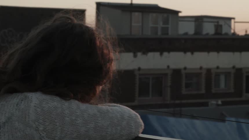 Man leans over a balcony looking at the city