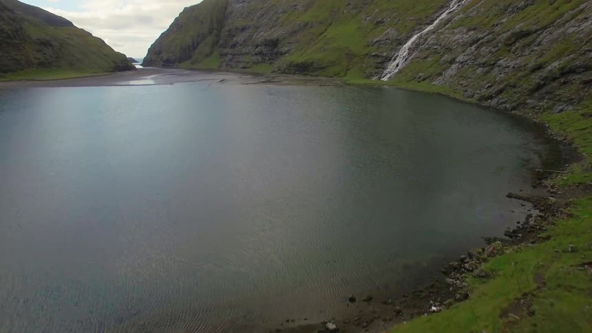 Sod hose at the edge of a lake surrounded by mountains
