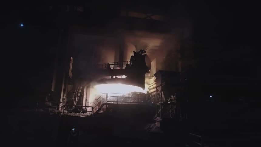 Steam billows from machinery in a dark factory