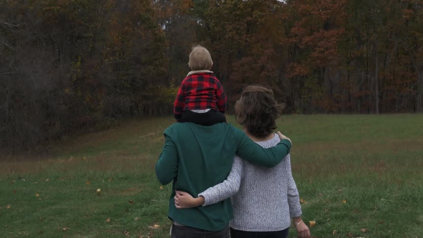 A man and woman walk with a baby on the man's shoulders