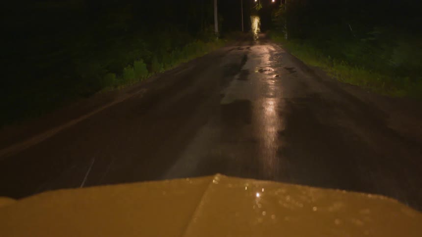 View looking through a car as it drives down a dark country road