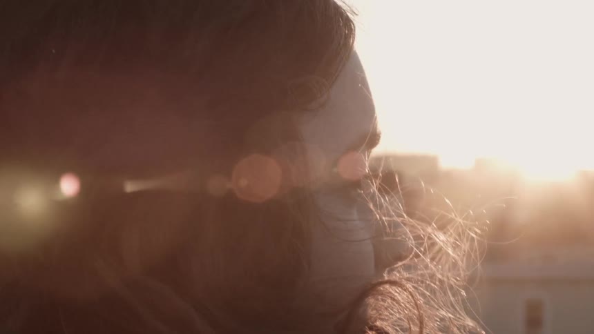 A woman looks over a field on a windy day