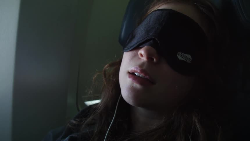 Woman wearing a sleeping mask on an airplane