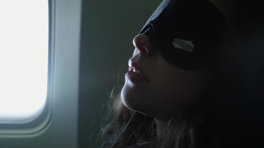 Woman wearing a sleeping mask on an airplane