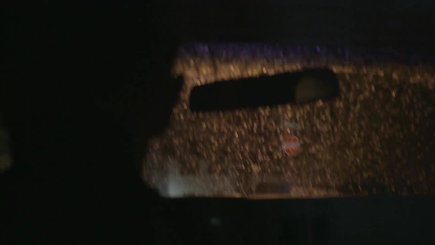 A car drives through a neighborhood on a rainy night