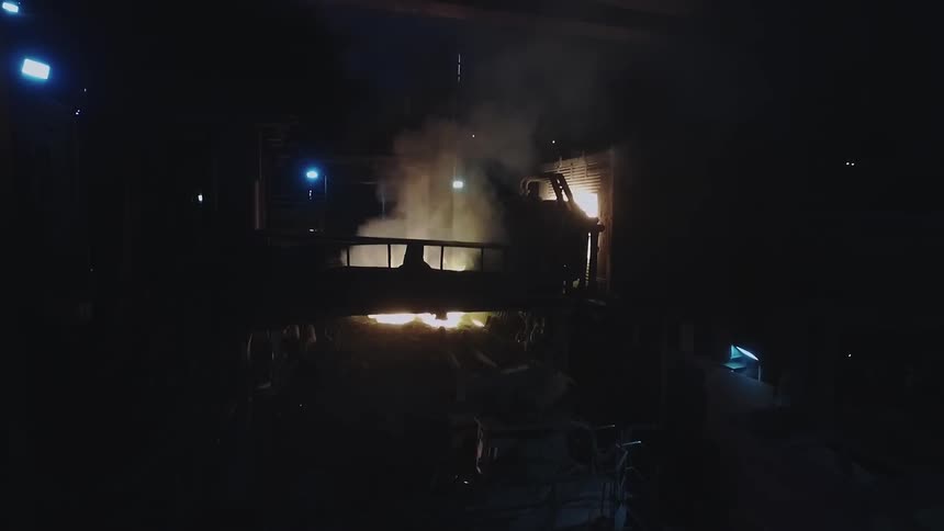 Steam and flames raise from a machine in the dark