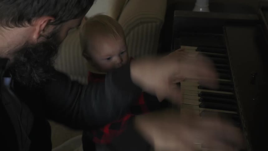 Man bangs on a piano with a baby