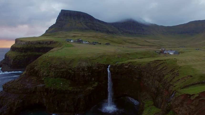 A waterfall pours off the tall cliff