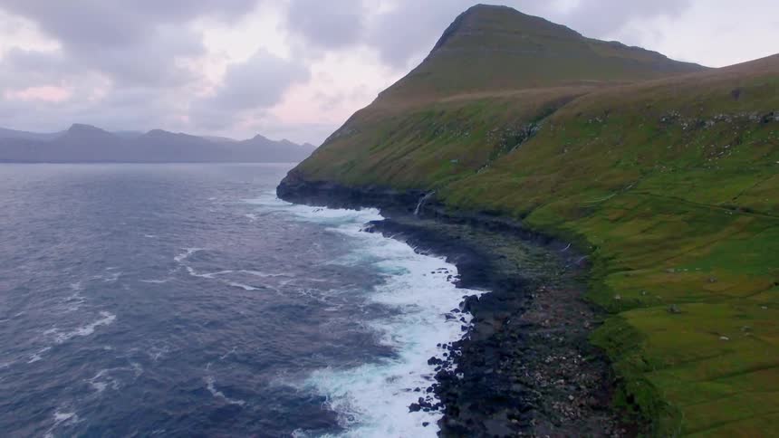 Ocean waves crash into a rocky shore on a cloudy day