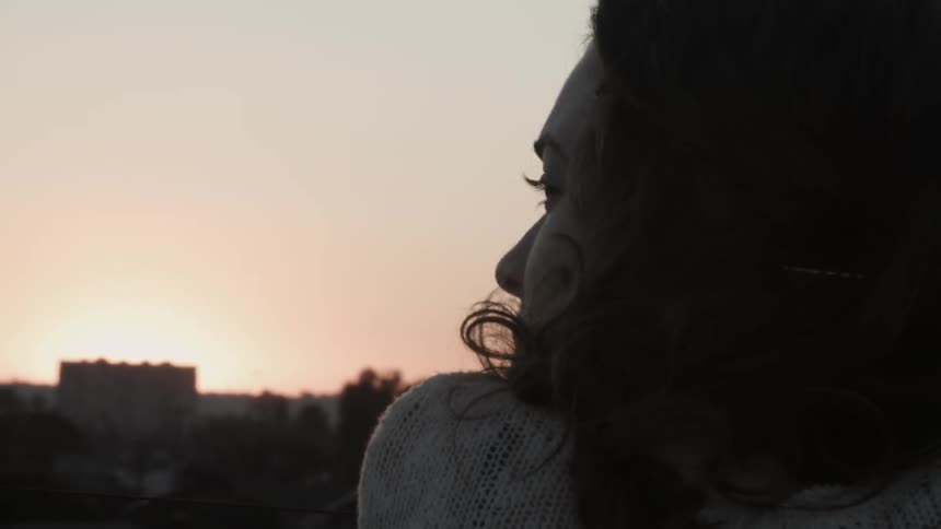 Woman looks outside at sunrise
