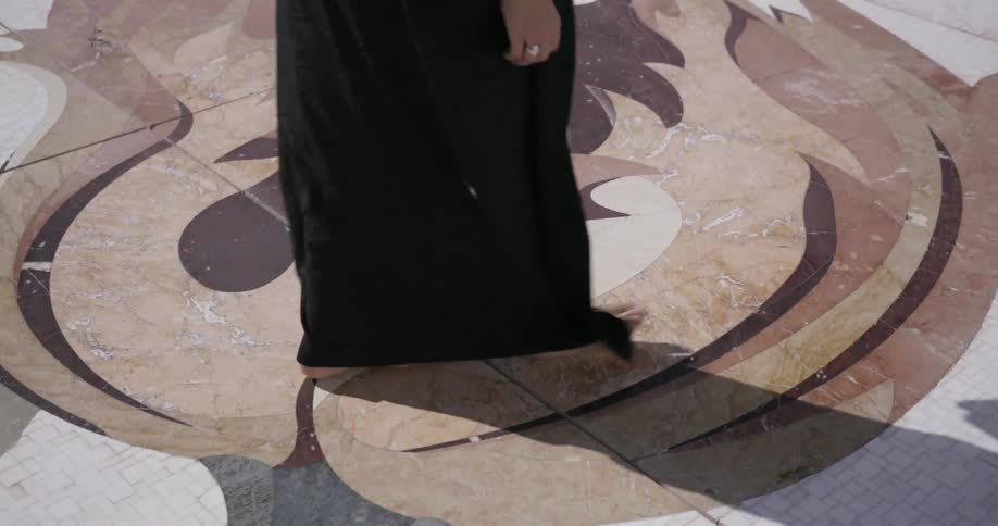 Barefooted person walks over ornate tile outside