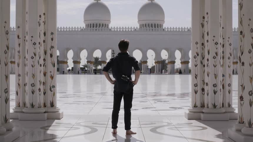 Man stands with hands on his hips looks out at a building