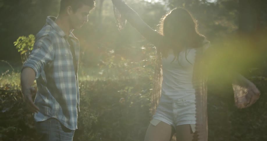 Man and woman smiling and holding hands in the woods on a sunny day