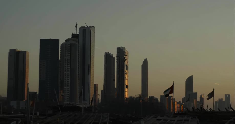 Flags waving in front of skyscrapers at sunset