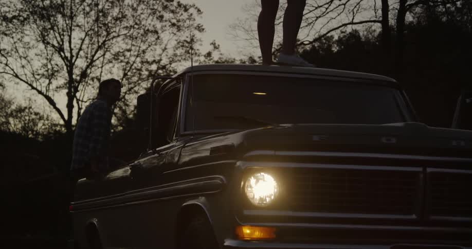 A man is sitting in the back of a pickup truck
