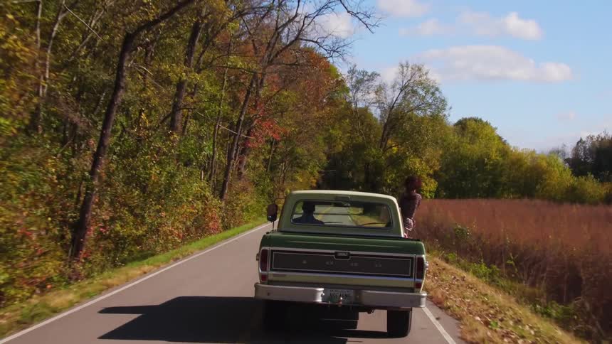 A woman is hanging out of a moving pickup truck