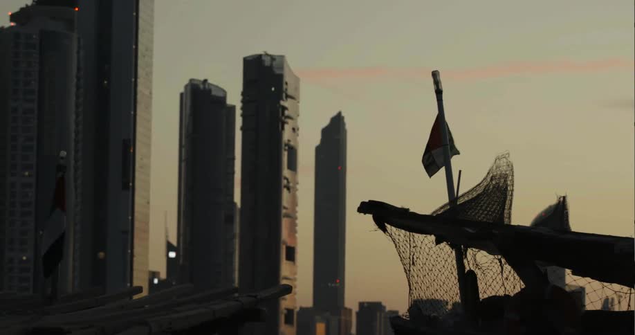Flag waves in front of large skyscrapers at sunset
