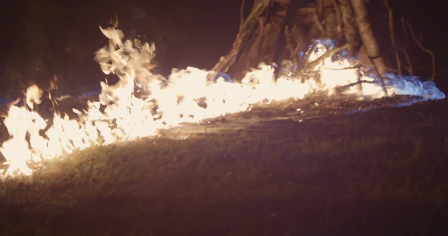 Fire burns quickly over grass to a pile of sticks