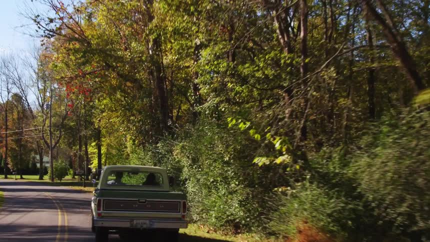 A pickup truck moves down the road on a sunny day