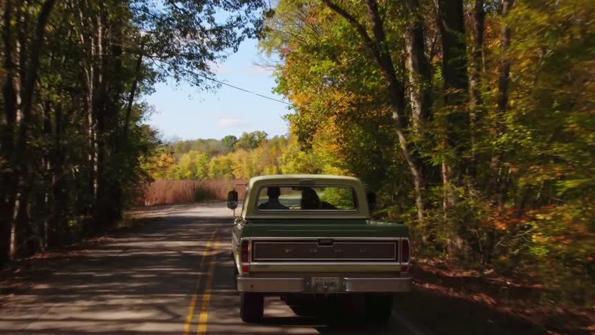 Two people riding in a truck down a country road